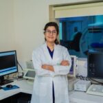Confident female doctor with arms crossed in a modern medical laboratory setting in Delhi, India.